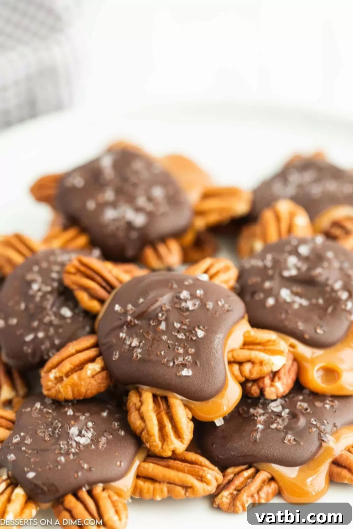 A perfectly arranged display of finished Chocolate Turtles, each with distinct pecan, caramel, and chocolate layers, and a hint of sea salt.