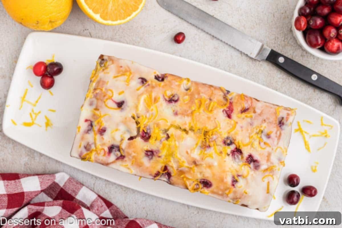 Zesty Orange Cranberry Loaf 2 Freshly baked Orange Cranberry Bread on a wooden platter, ready to be sliced and served, highlighting its golden crust and juicy cranberry speckles.