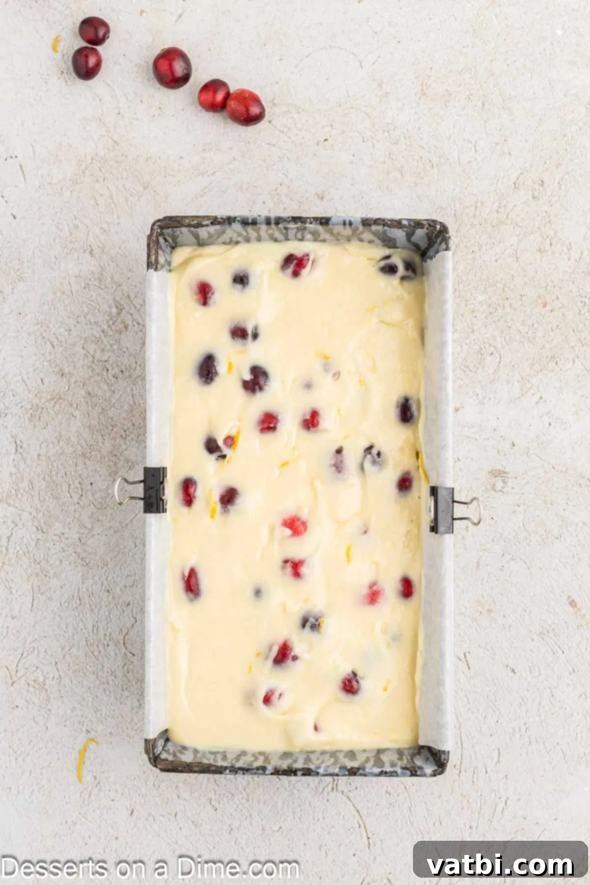 Zesty Orange Cranberry Loaf 7 Orange cranberry bread batter with cranberries folded in, being poured into a parchment-lined loaf pan for baking.