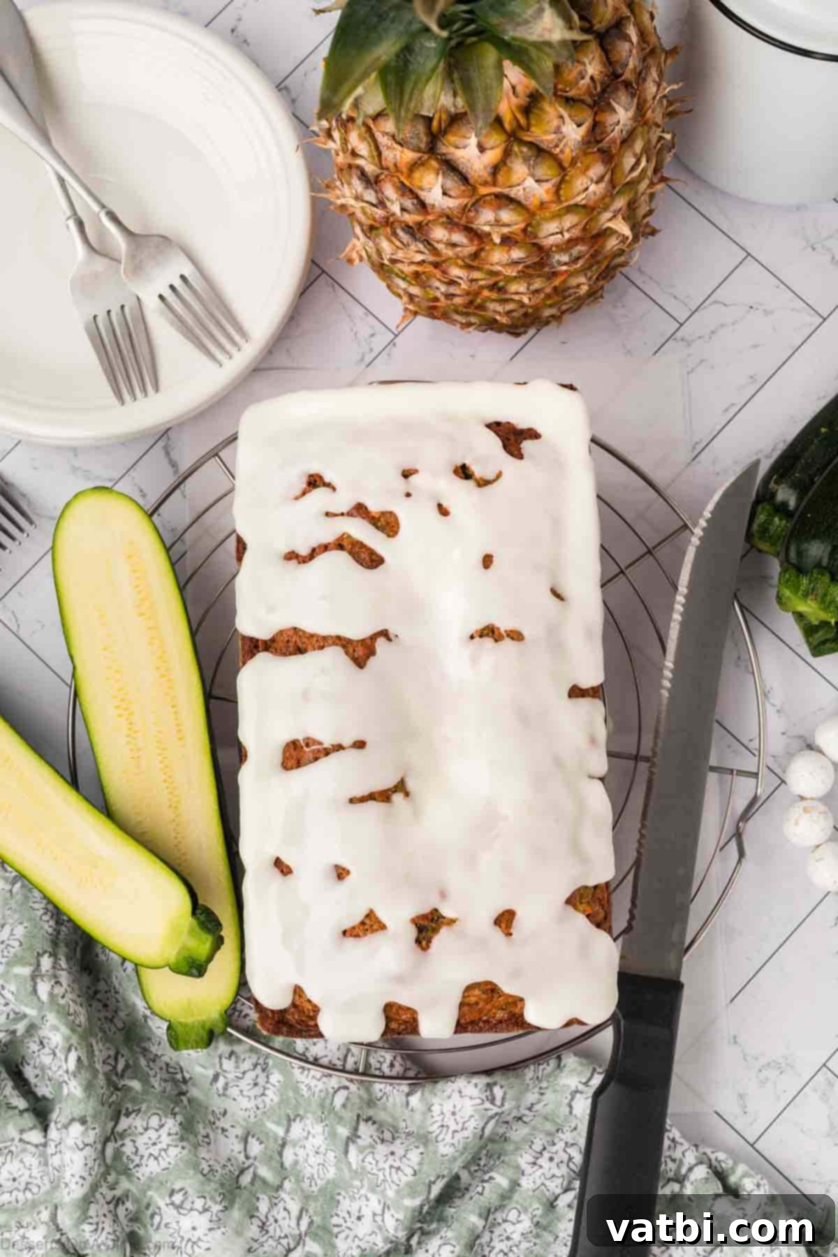 A slice of glazed Zucchini Pineapple Bread on a plate, with the rest of the loaf behind it.