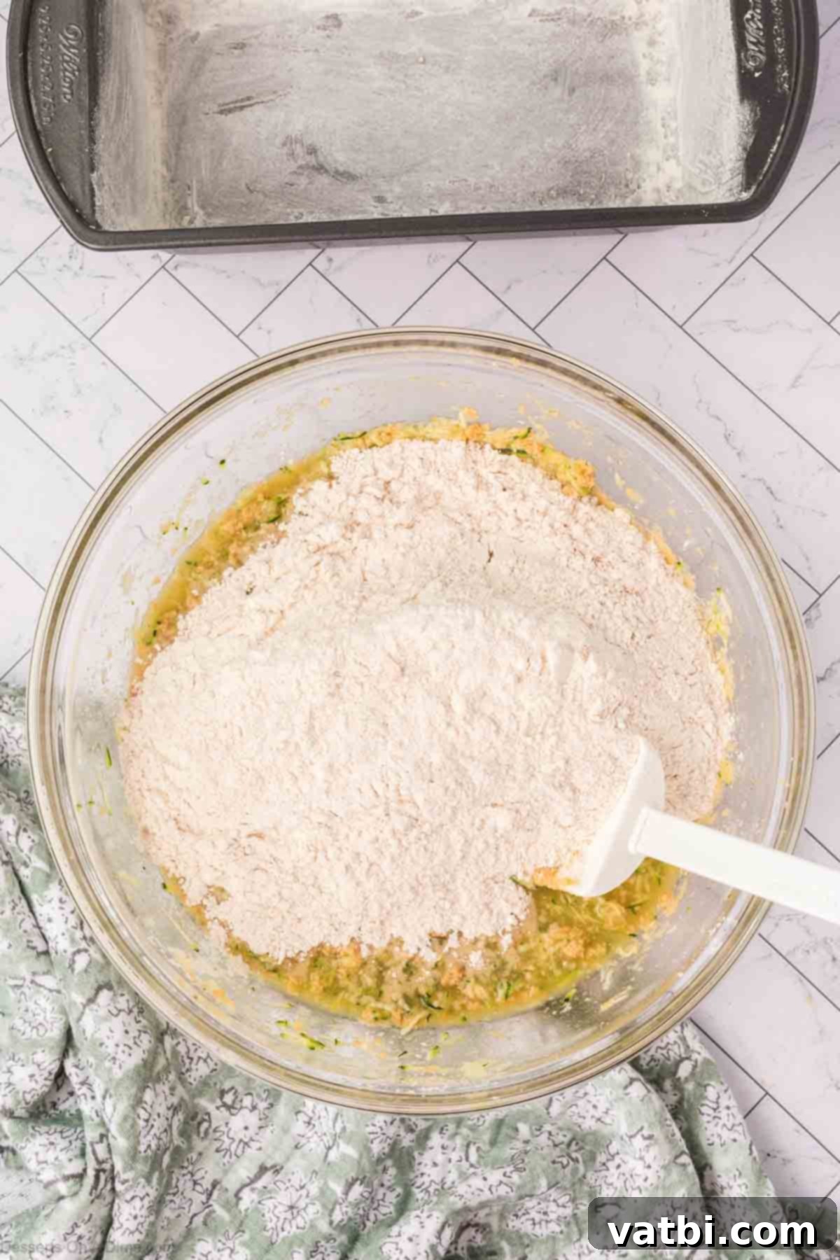 Wet and dry ingredients combined in a mixing bowl to form a thick batter.