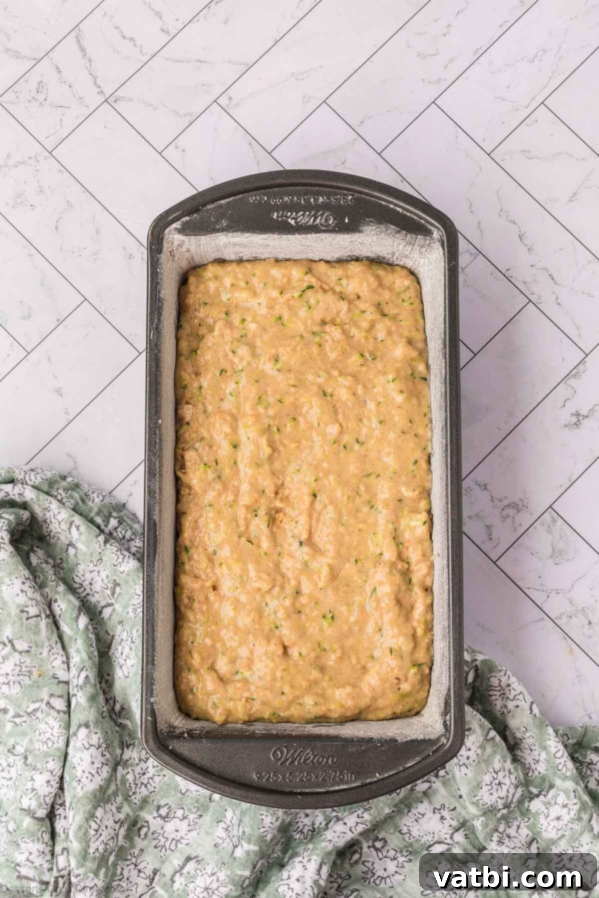 Zucchini pineapple bread batter poured into a prepared loaf pan.