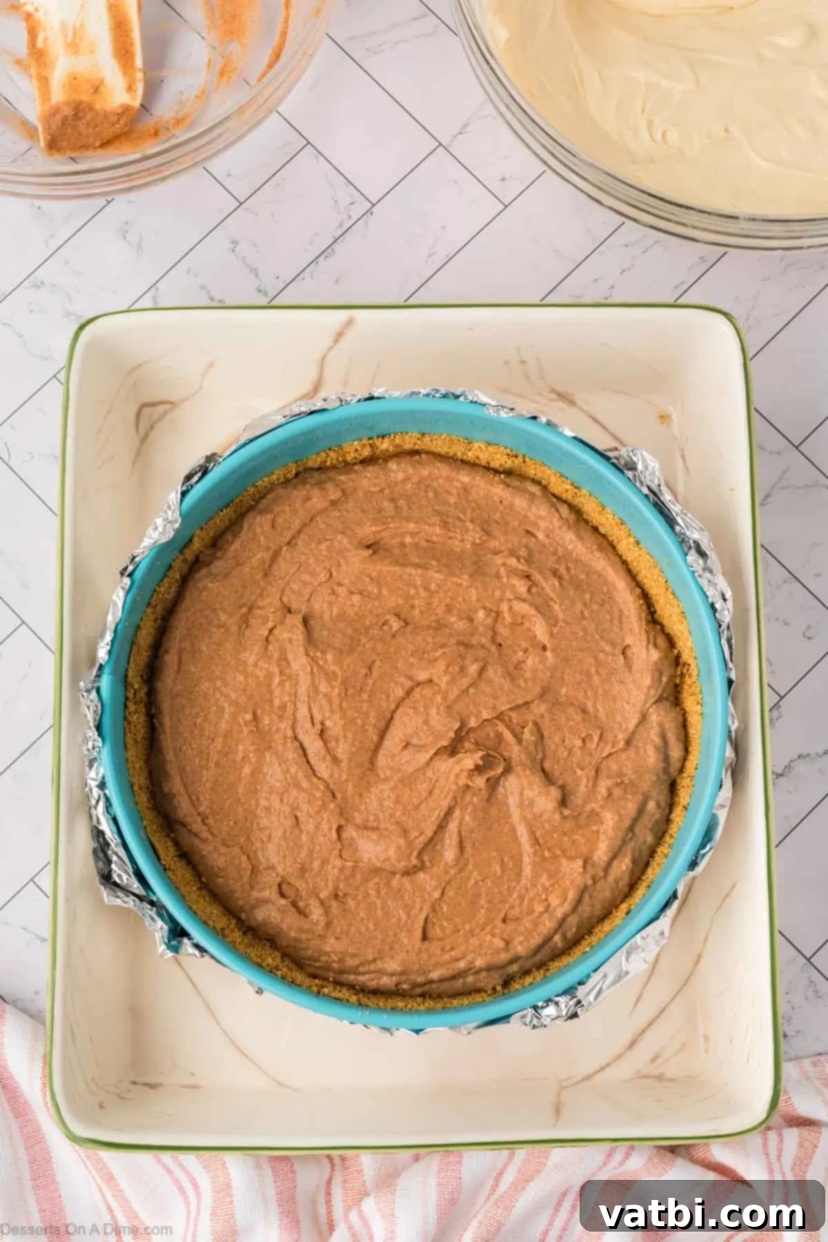 The sweet potato cheesecake layer evenly spread over the graham cracker crust in the springform pan, ready for the next layer.