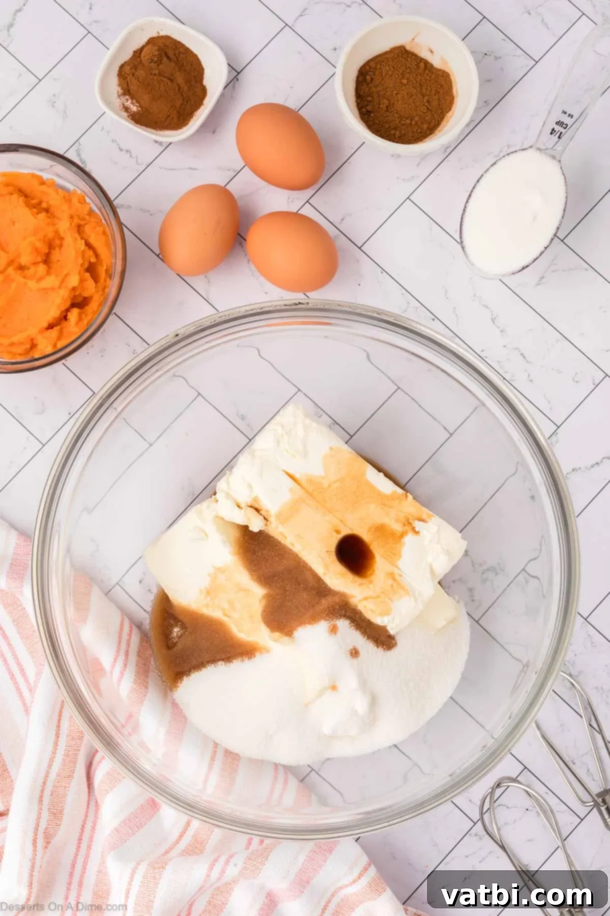Cream cheese, granulated sugar, and vanilla extract being beaten together in a large mixing bowl until smooth.