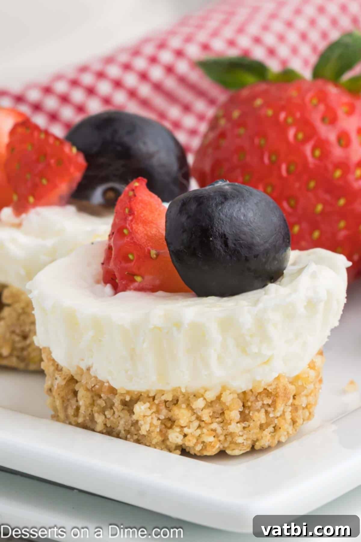 A close-up shot of several mini cheesecakes topped with a generous assortment of fresh berries, highlighting their creamy texture and vibrant colors.