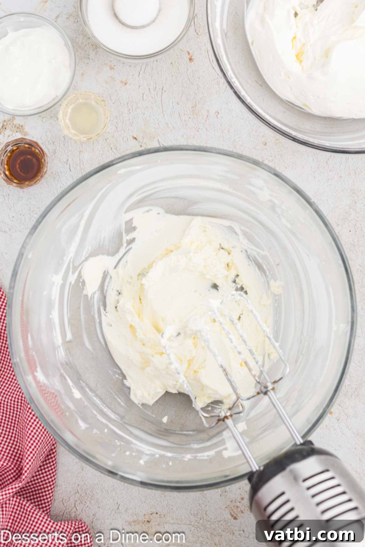 Cream cheese being beaten until fluffy in a separate mixing bowl, ensuring a smooth and lump-free base for the cheesecake filling.